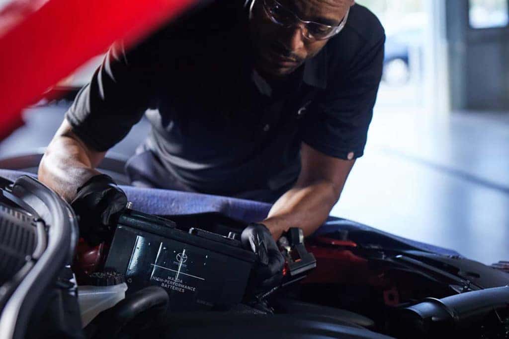 Service technician works under the hood of a red Mazda