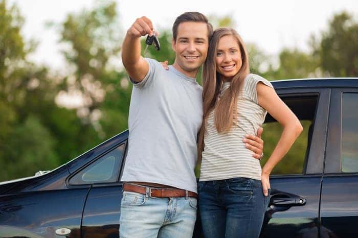 Couple stands in front of car and holds up keys