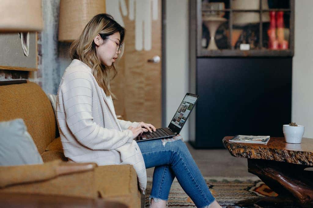 Woman shopping for a used car online while sitting on her couch.