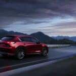 Red 2021 Mazda CX-5 driving down the highway at dusk
