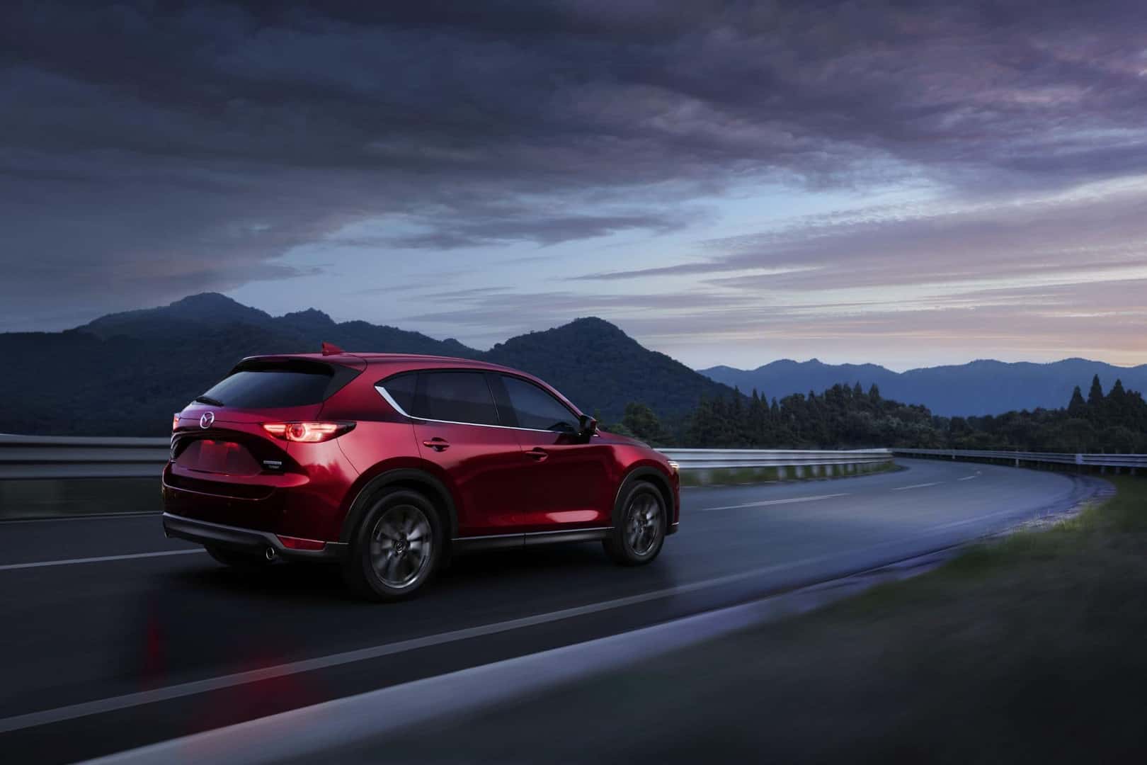 Red 2021 Mazda CX-5 driving down the highway at dusk