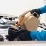Service technician hands pouring oil into a funnel