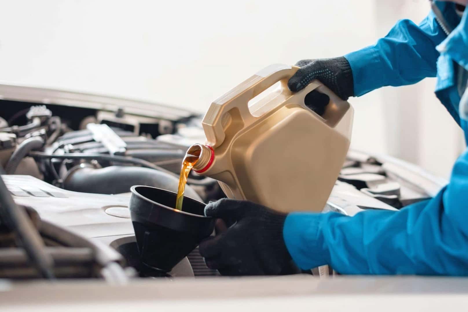 Service technician hands pouring oil into a funnel