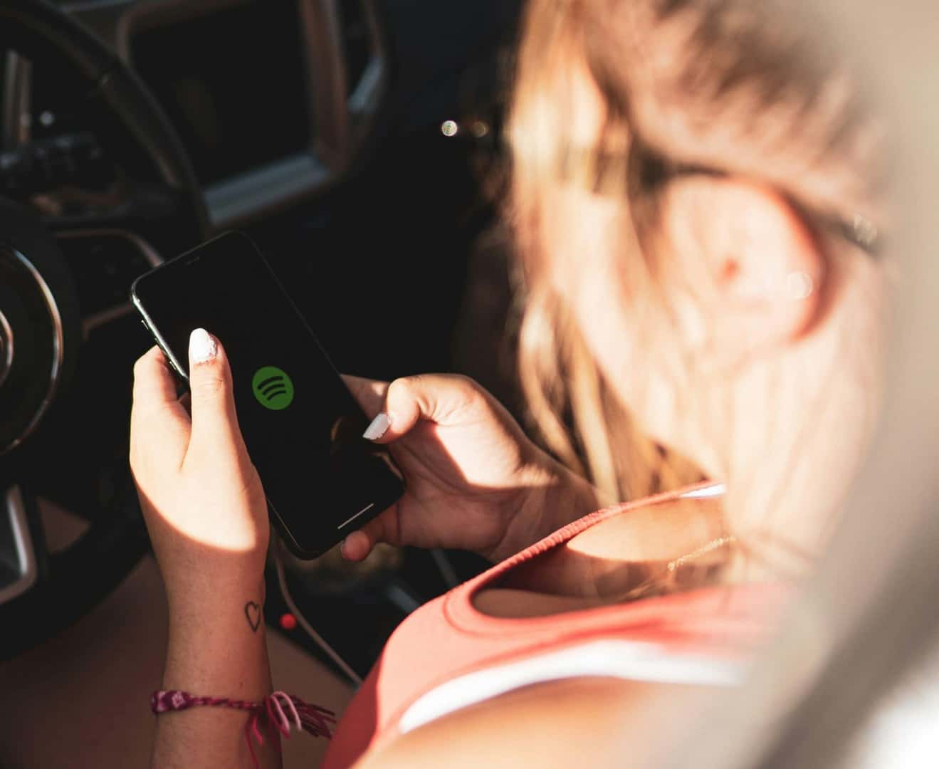 Girl in driver's seat of car using Spotify on her smartphone