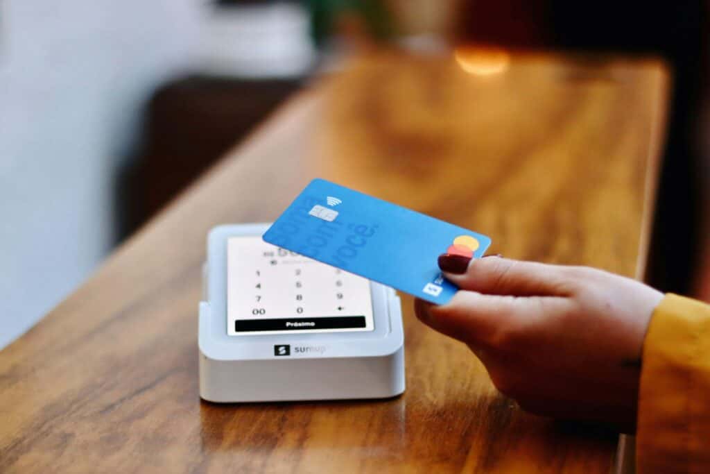 hand with painted fingernails paying for something at a counter with a credit card