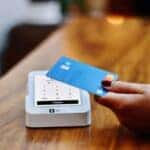 hand with painted fingernails paying for something at a counter with a credit card