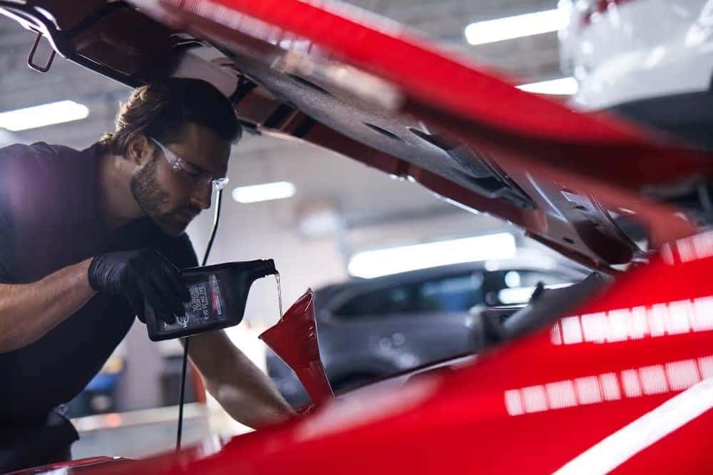 Mazda Mechanic Pouring Oil into a Vehicle