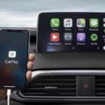 hand holding phone plugged into infotainment system running Apple CarPlay