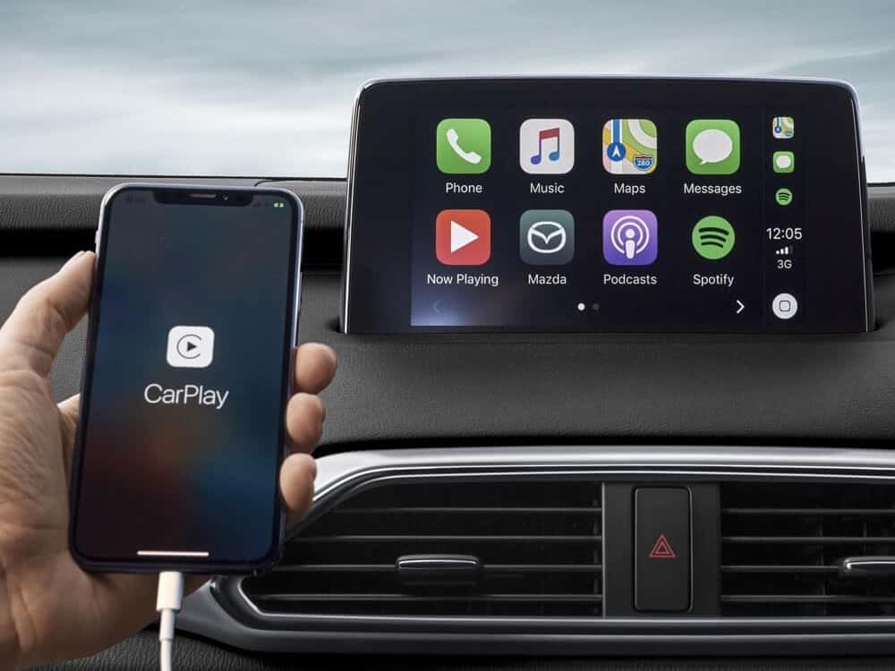 hand holding phone plugged into infotainment system running Apple CarPlay