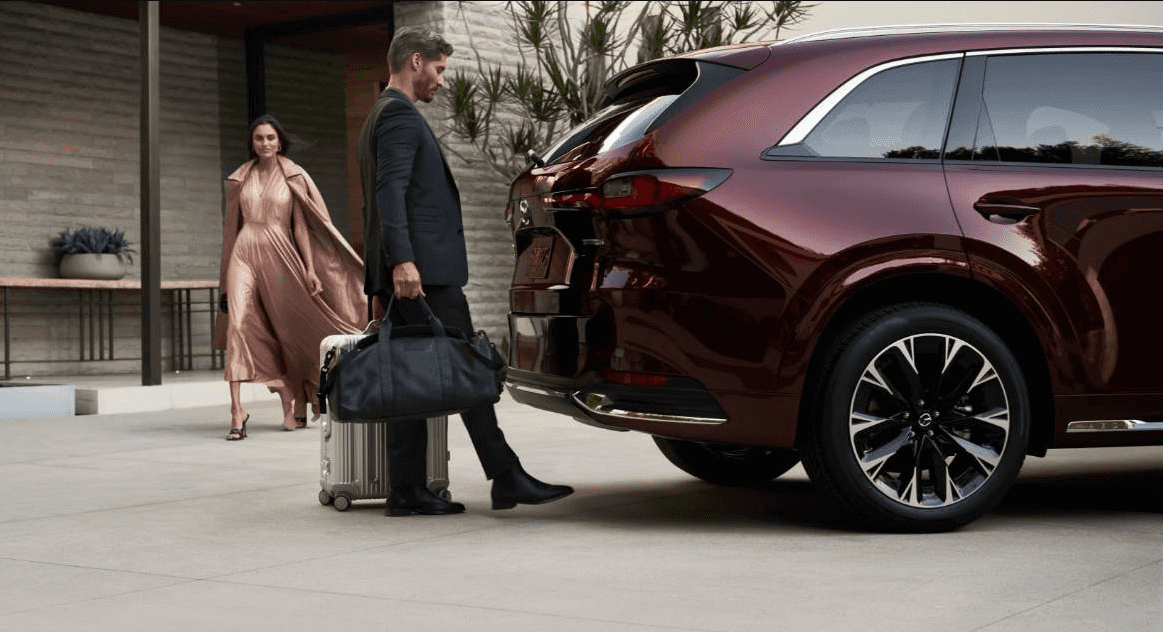 Man opening mazda trunk to place bags and suitcase inside