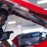 Mazda service technician doing an oil change under hood