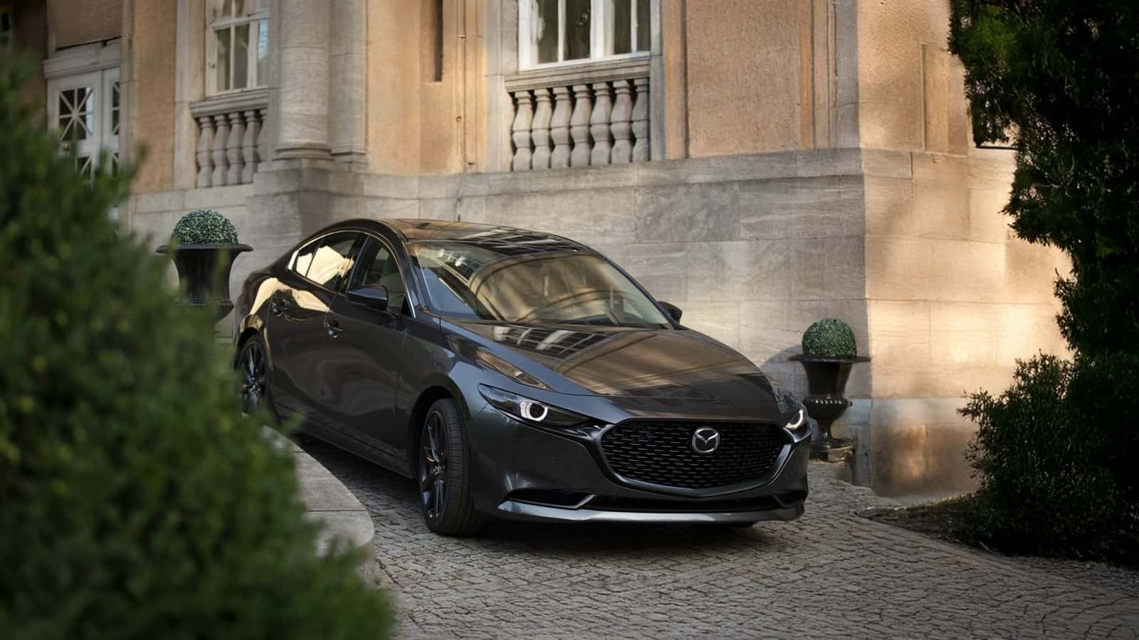 Black Mazda 3 Sedan parked next to building