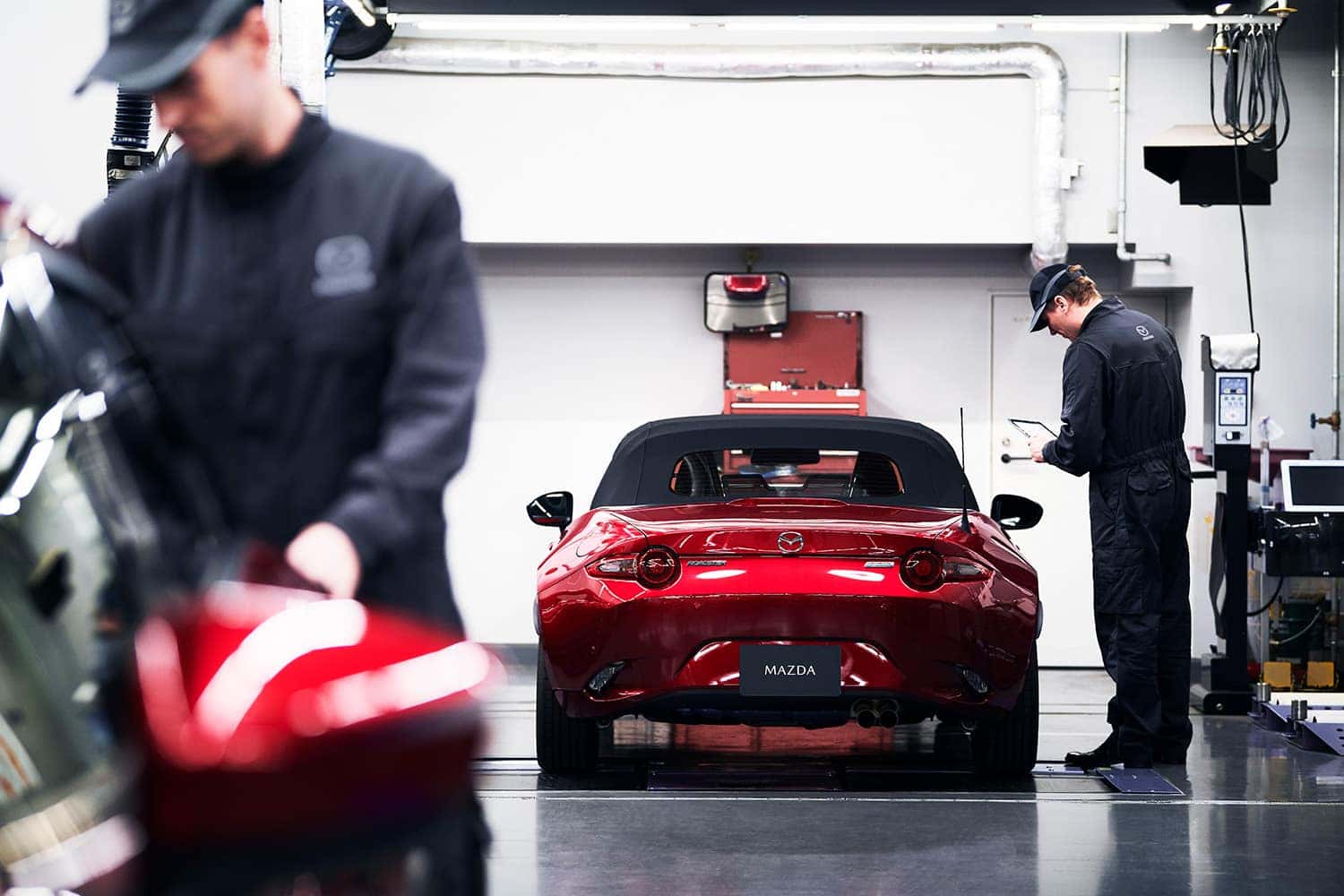 Red car in a service bay with two service workers
