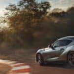 A 2020 Toyota Supra drifts around a corner while the sun shines down on the track.