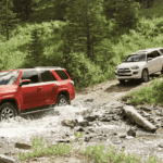 two toyota 4runner models off-roading in forest