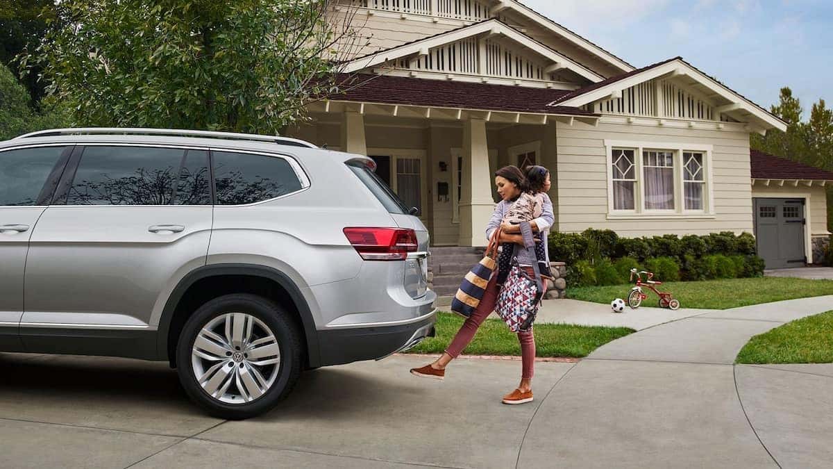 A woman hold a child and several bags takes advantage of the Power Liftgate feature of the Atlas.