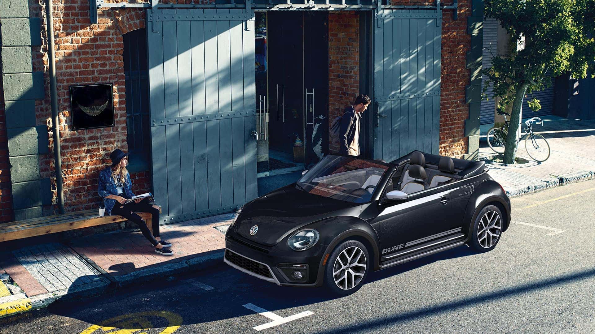 2019 VW Beetle Convertible Dune parked next to a couple of disinterested youths.