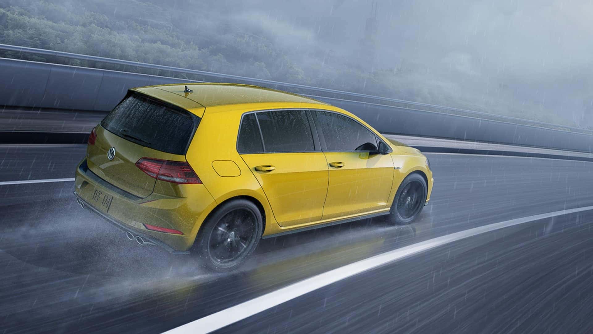 A yellow 2019 VW Golf R drives quickly and confidently through the rain.