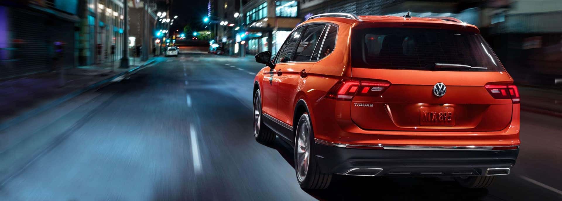 Red 2019 VW Tiguan driving down a street at night